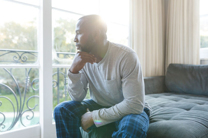 Worried, sad african american man thinking, sitting on couch loo