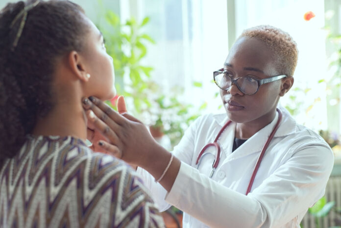 African girl in a white coat, with a phonendoscope, wearing glasses, examines a Mexican girl patient with a sore throat. The concept of tonsillitis, sore throat, complications of the flu, in the form of tonsillitis, pharyngitis