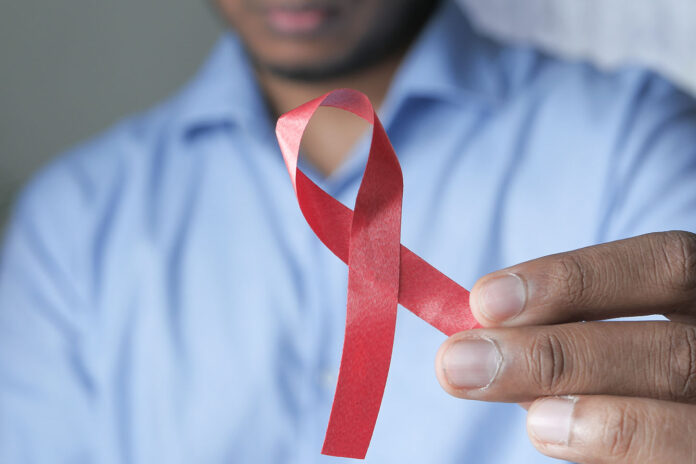 hand holding red HIV ribbon with copy space .